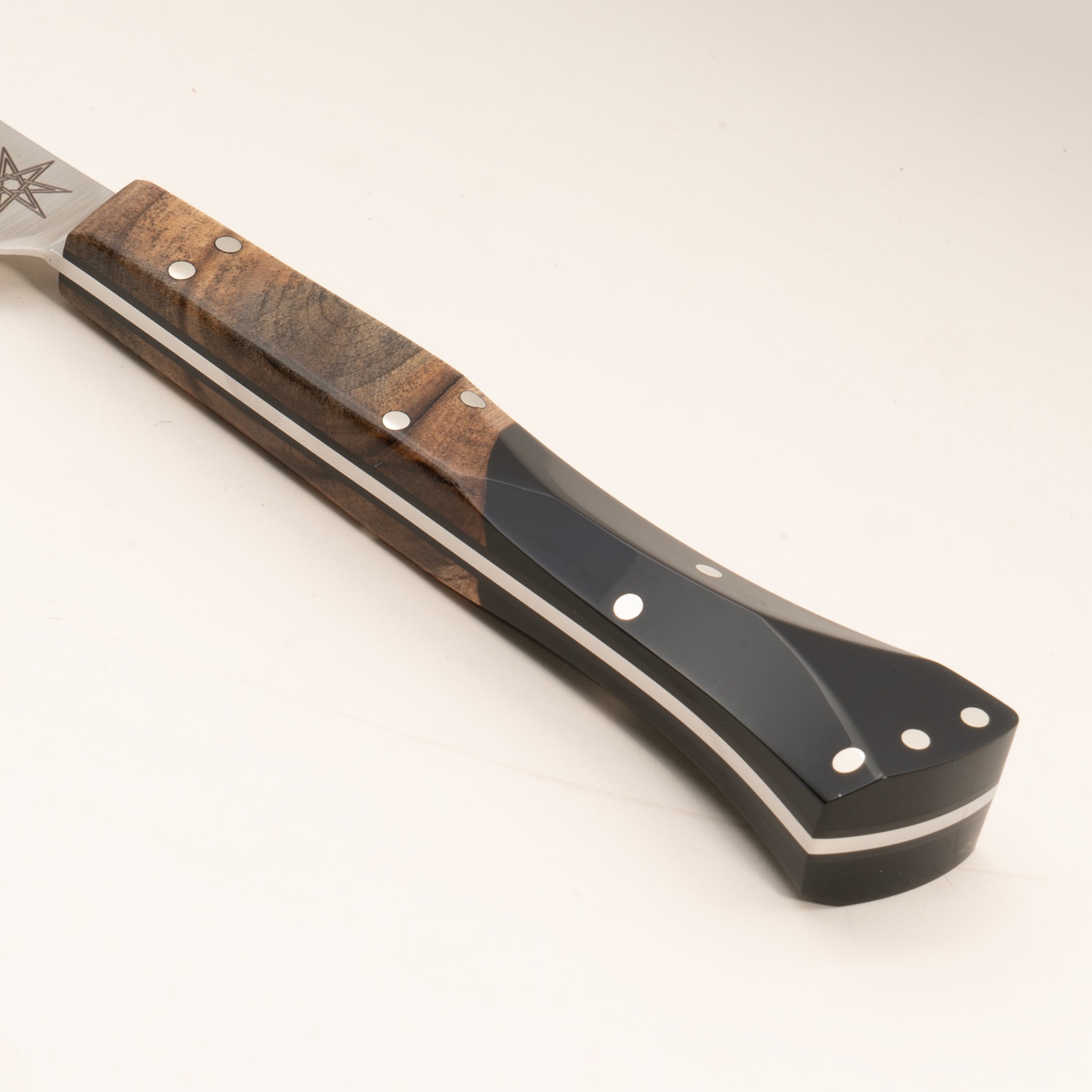 Close-up of a kitchen bird's beak knife handle made from wood and black resin, on a white background.