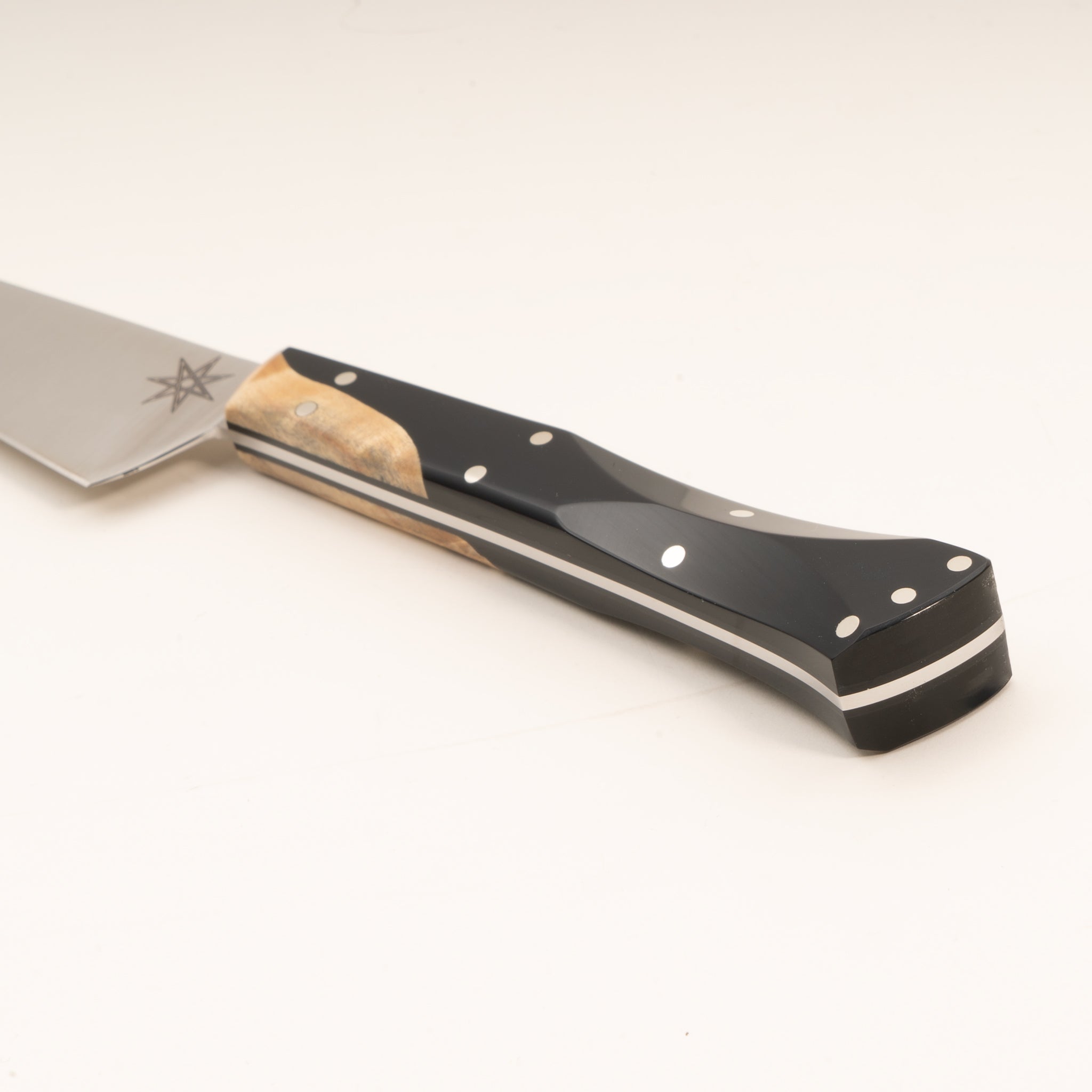Close-up of a kitchen paring knife handle made from wood and black resin, on a white background.