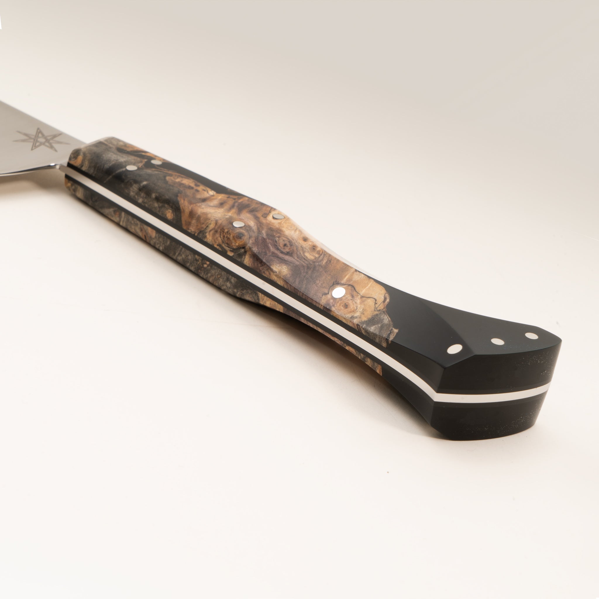 Close-up of a kitchen utility knife handle made from wood and black resin, on a white background.