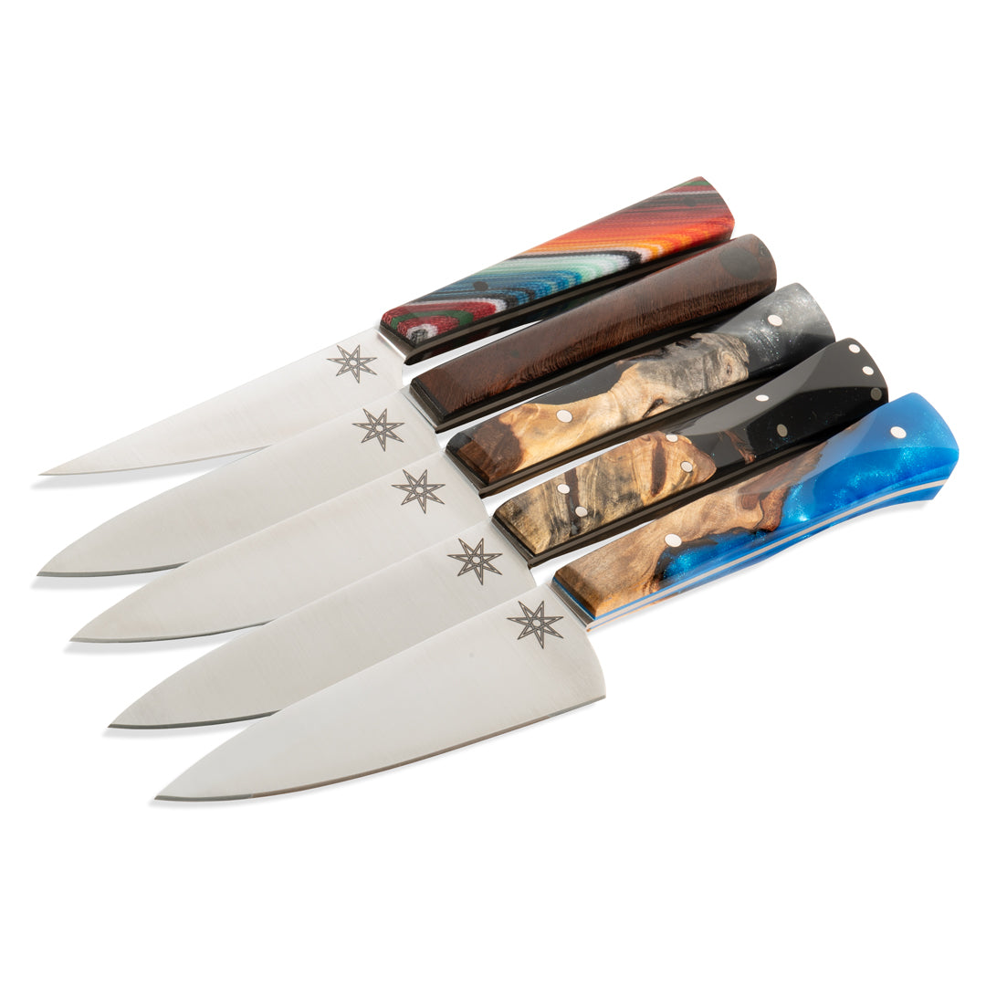 Five kitchen paring knives with different colors handles on a white background.