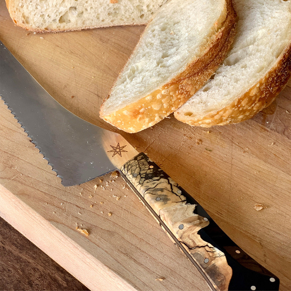 Town Cutler Desert Dawn Bread Knife on cutting board with slices of sourdough bread.
