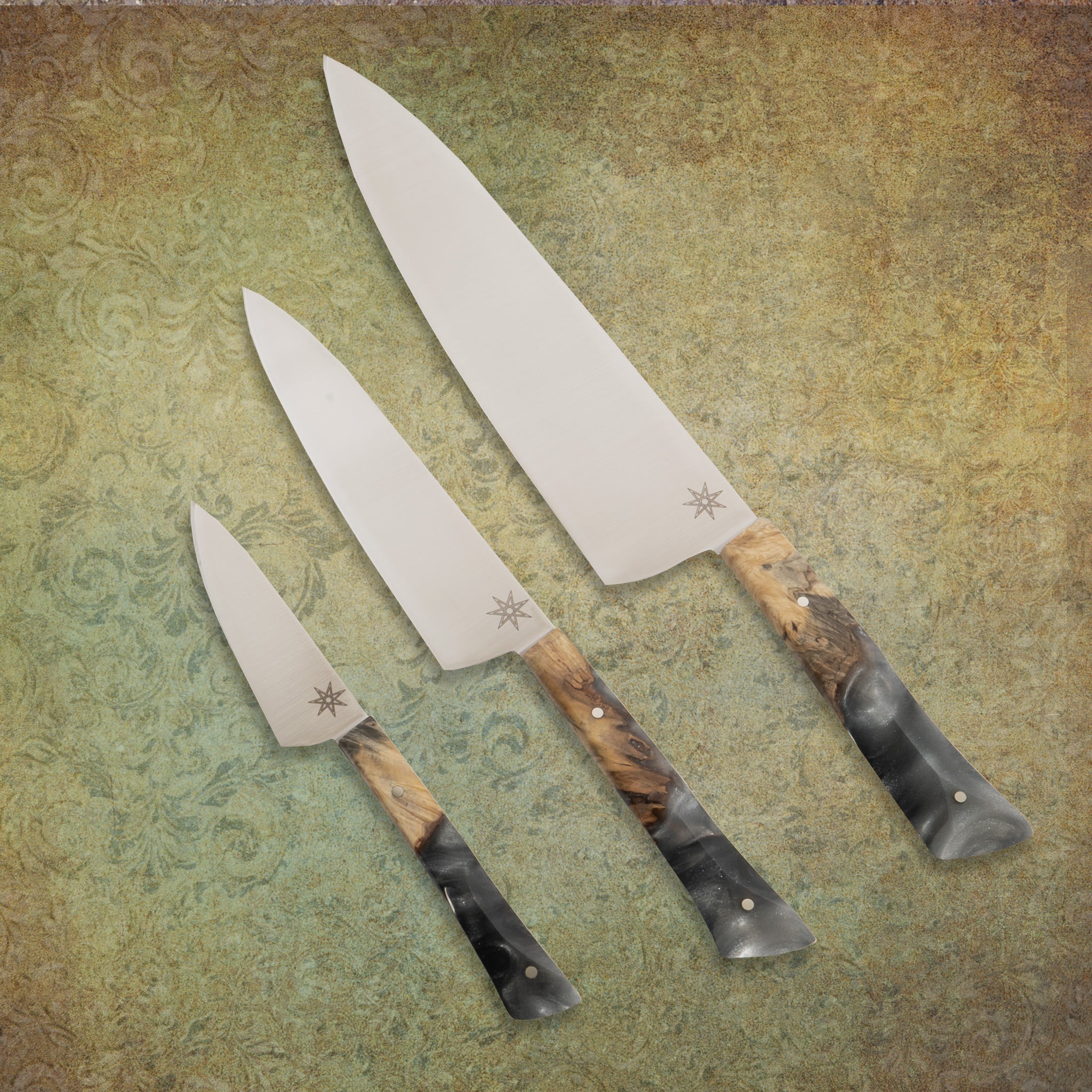 Three-piece handcrafted kitchen knife set with gray silver resin handles and wood.